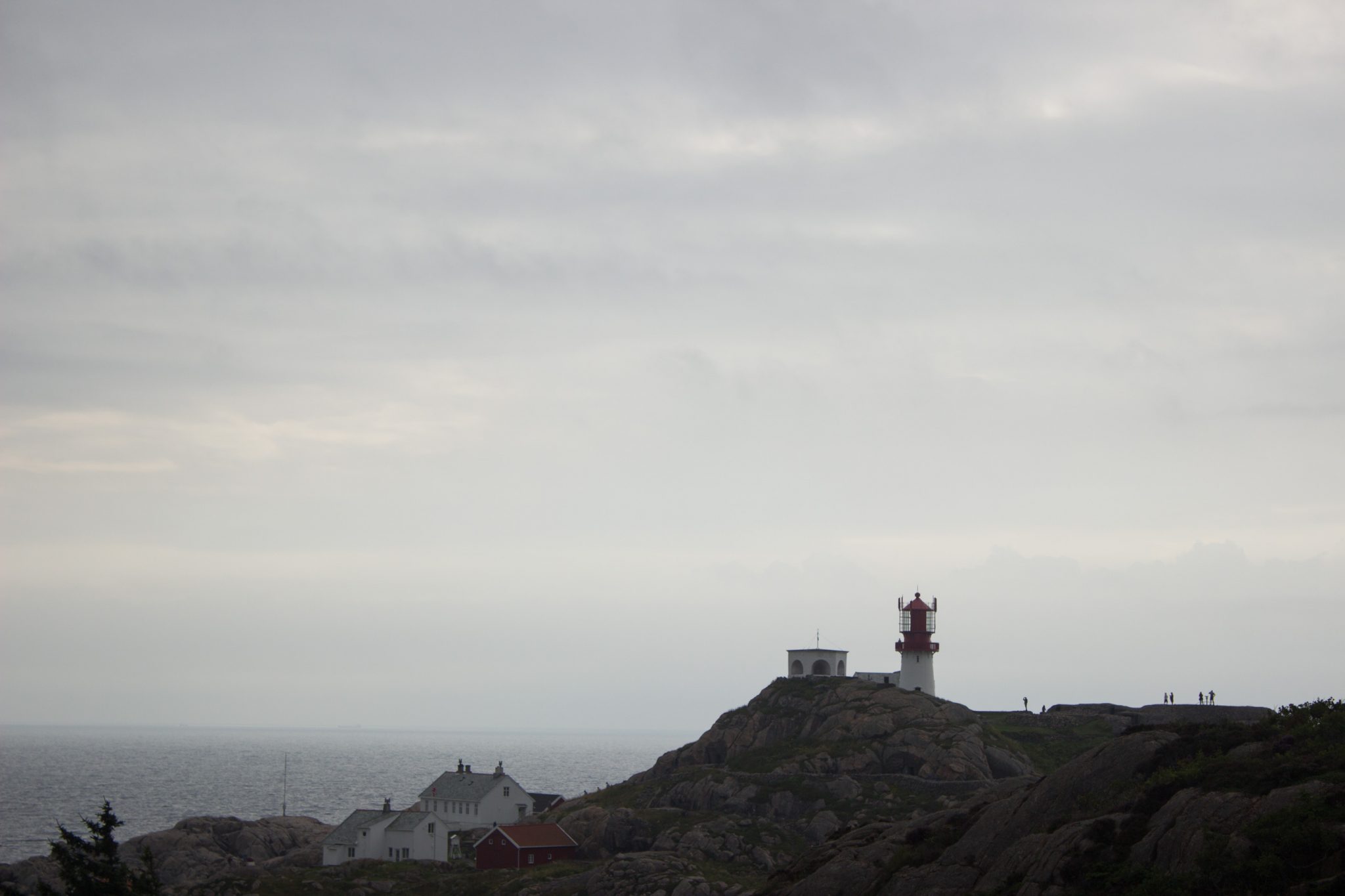 Wanderungen beim Kap Lindesnes, südlichster Punkt Norwegens, am Südkap in Norwegen, während der Wanderung Aussicht auf den Leuchtturm und ein paar Häuser, dahinter das weite Meer