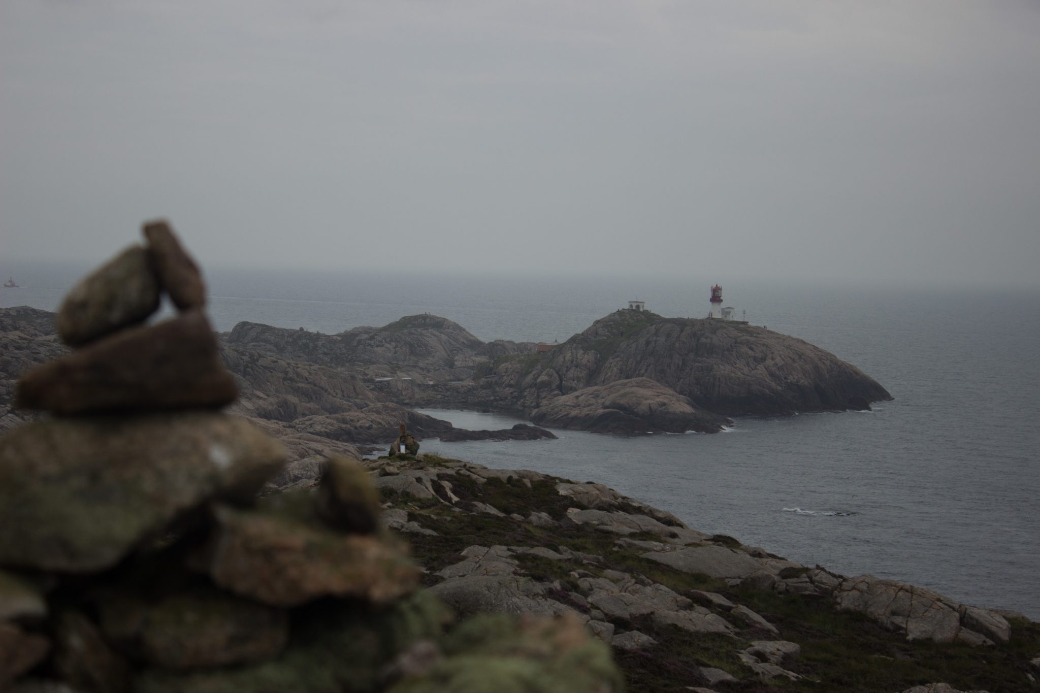 Wanderungen beim Kap Lindesnes, südlichster Punkt Norwegens, am Südkap in Norwegen, Wanderer genießt die Aussicht auf das weite Meer während der Wanderung beim Leuchtturm Lindesnes Fyr, unterwegs auf schmalem Pfad entlang großer Felsen, grüne Vegetation an der Küste