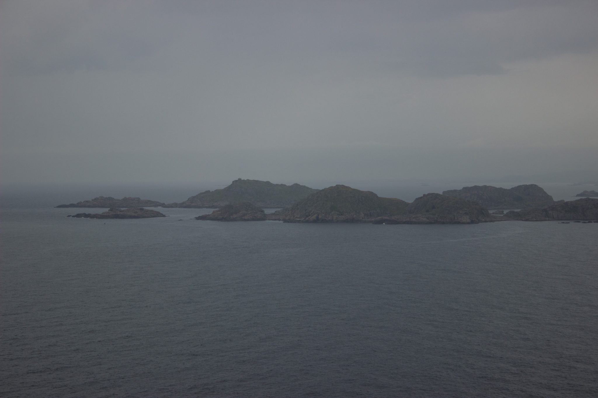 Wanderungen beim Kap Lindesnes, südlichster Punkt Norwegens, am Südkap in Norwegen, Wanderer genießt die Aussicht auf das weite Meer und die kleinen vorgelagerten Inseln während der Wanderung beim Leuchtturm Lindesnes Fyr