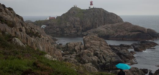 Wanderungen beim Kap Lindesnes, südlichster Punkt Norwegens, am Südkap in Norwegen, Wanderer im Regen unterwegs auf schmalem Pfad entlang großer Felsen, teils sehr sumpfiger Weg, grüne Vegetation an der Küste, Heidelandschaft, Aussicht auf das weite Meer und den Leuchtturm Lindesnes Fyr