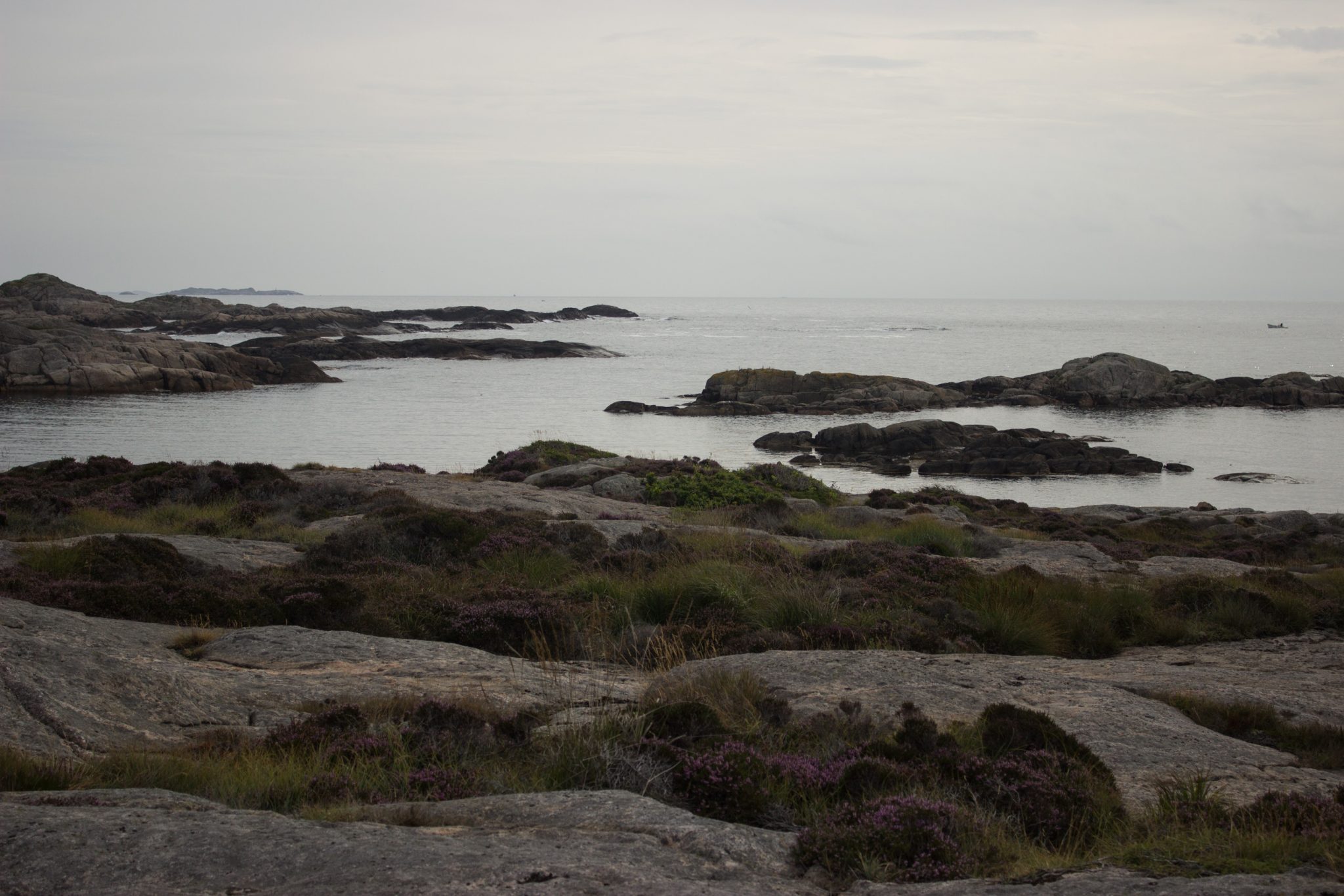 Wanderungen beim Kap Lindesnes, südlichster Punkt Norwegens, Leuchtturm Lindesnes Fyr am Südkap in Norwegen, Wanderer unterwegs auf schmalem Pfad entlang großer Felsen, grüne Vegetation an der Küste, Heidelandschaft, Aussicht auf das weite Meer