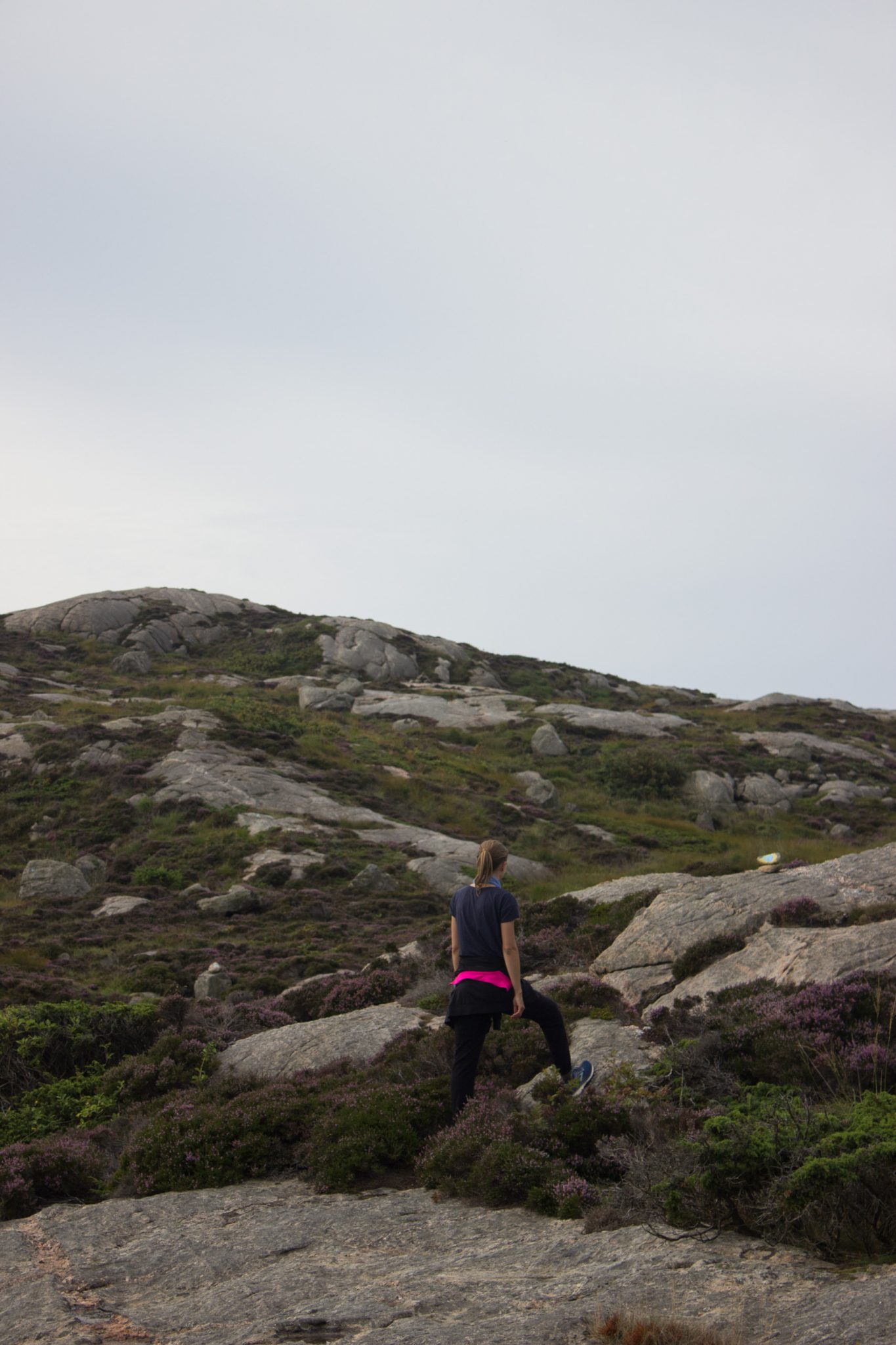 Wanderungen beim Kap Lindesnes, südlichster Punkt Norwegens, Leuchtturm Lindesnes Fyr am Südkap in Norwegen, Wanderer unterwegs auf schmalem Pfad entlang und über große Felsen, grüne Vegetation an der Küste, Heidelandschaft