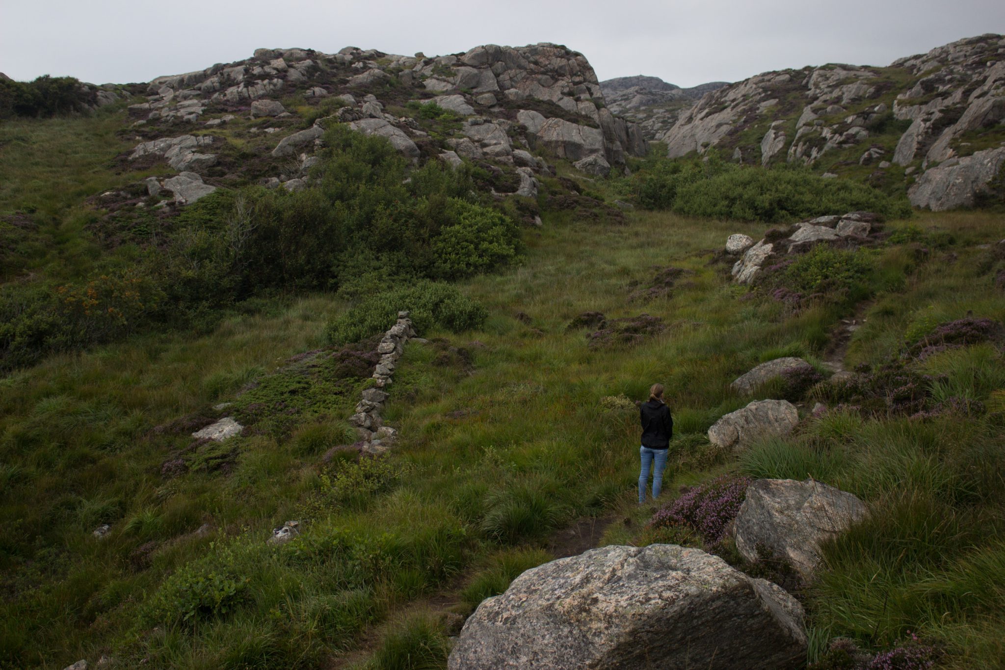 Wanderungen beim Kap Lindesnes, südlichster Punkt Norwegens, am Südkap in Norwegen, Wanderer unterwegs auf schmalem Pfad entlang großer Felsen, grüne Vegetation an der Küste, Heidelandschaft