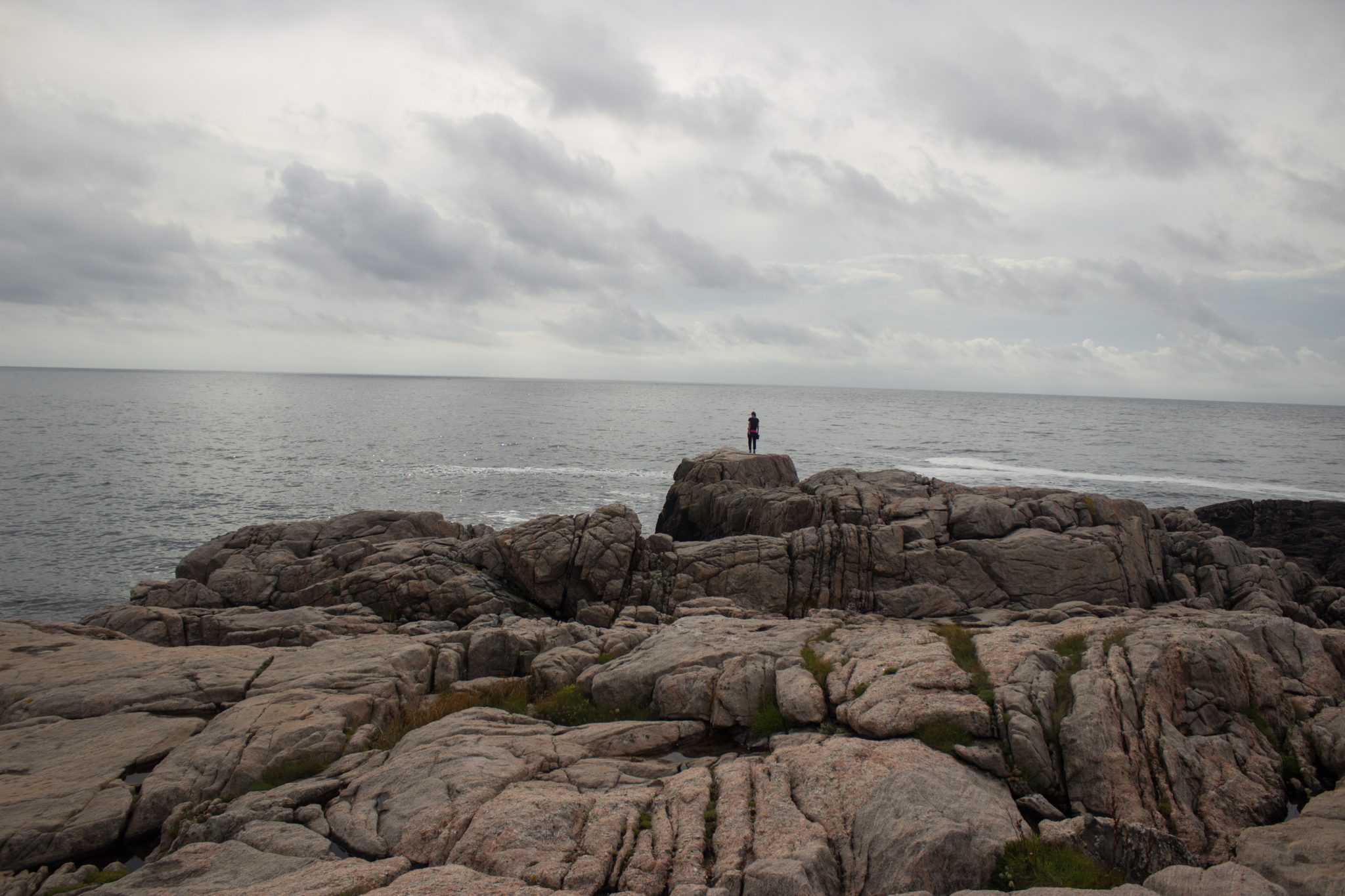 Wanderungen beim Kap Lindesnes, südlichster Punkt Norwegens, Leuchtturm Lindesnes Fyr am Südkap in Norwegen, Wanderer unterwegs auf Wanderweg entlang und über große Felsen, Aussicht auf das weite Meer