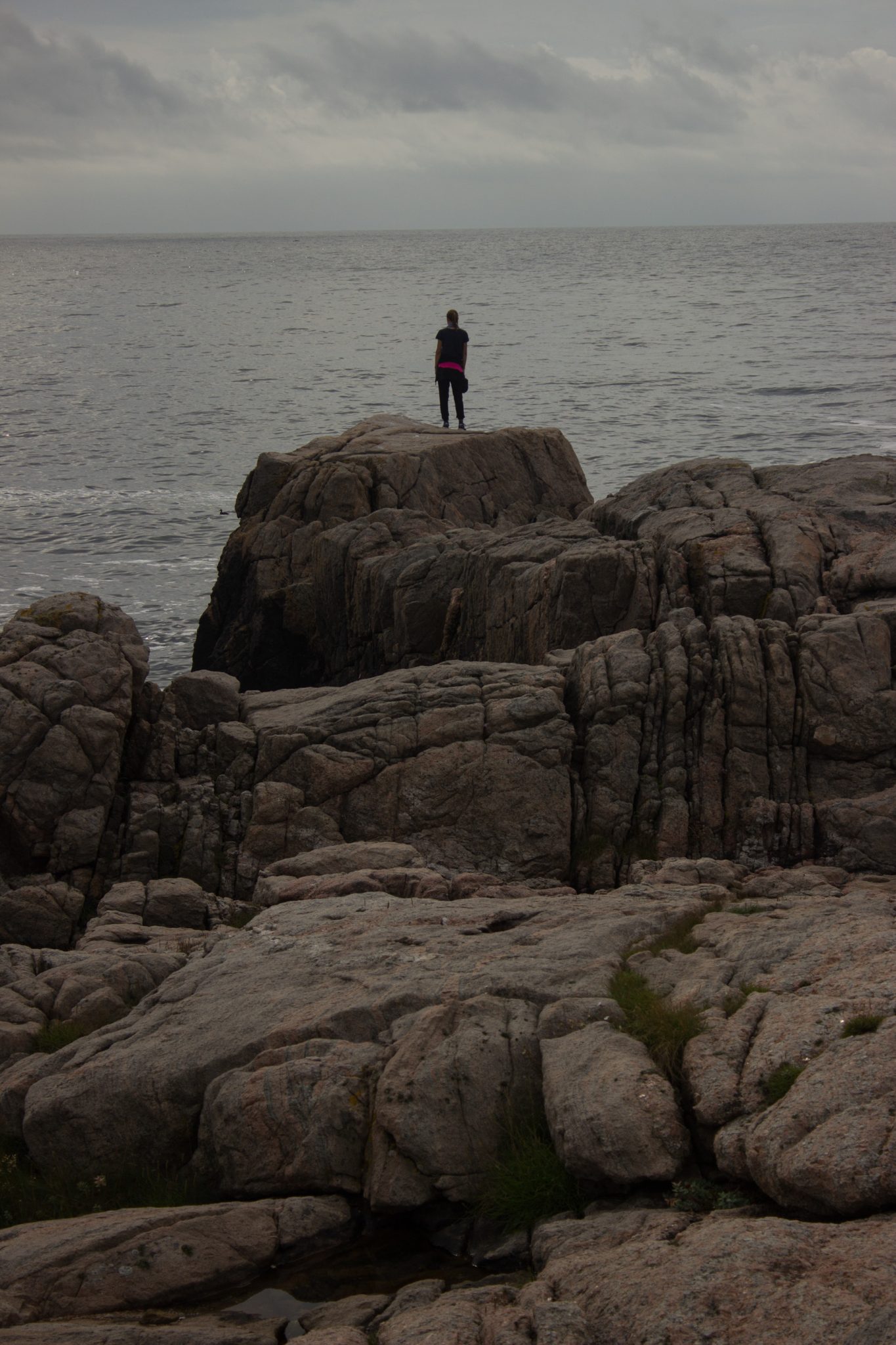 Wanderungen beim Kap Lindesnes, südlichster Punkt Norwegens, Leuchtturm Lindesnes Fyr am Südkap in Norwegen, Wanderer genießt die Aussicht von einem großen Felsen auf das weite Meer