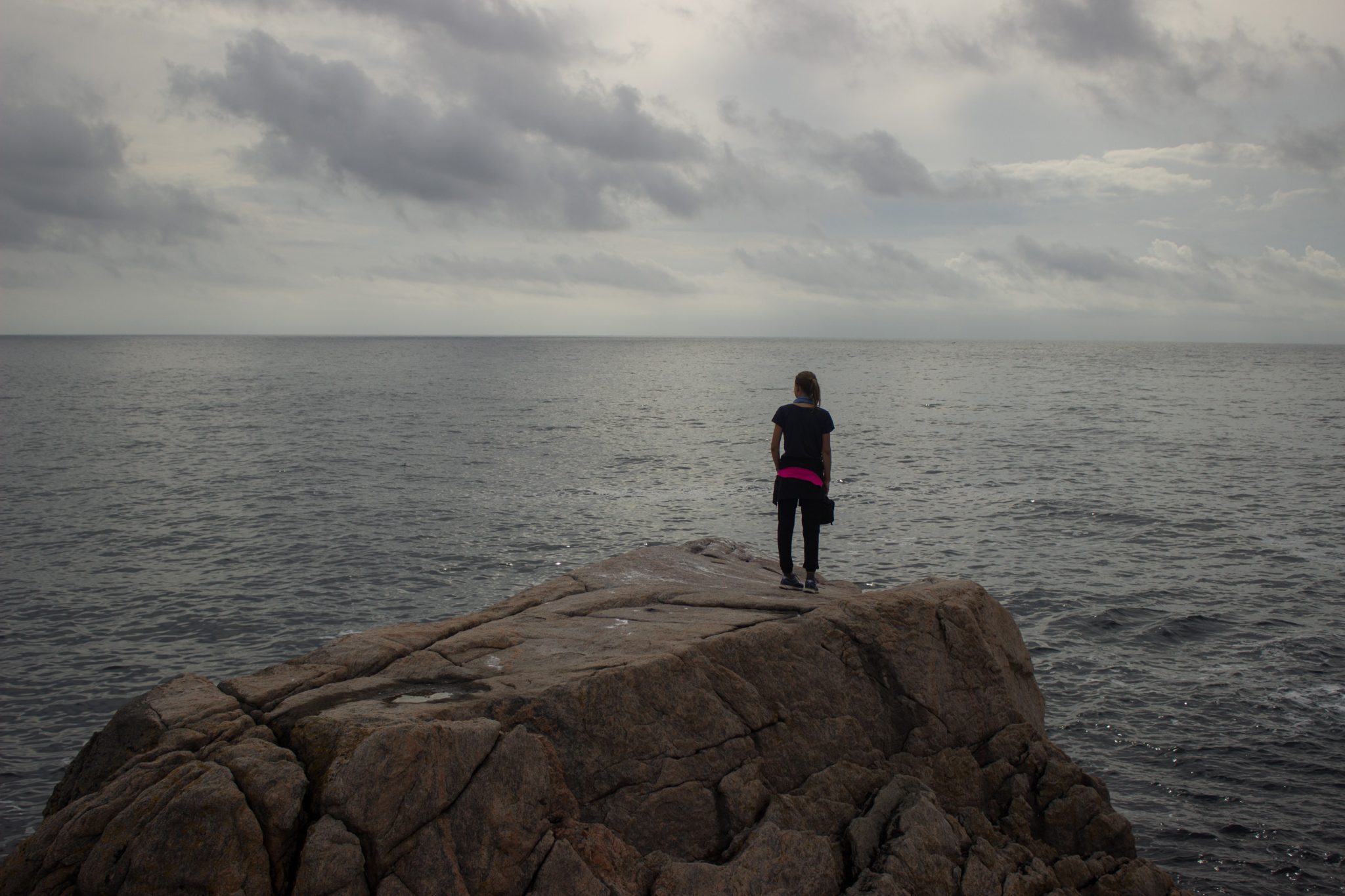 Wanderungen beim Kap Lindesnes, südlichster Punkt Norwegens, Leuchtturm Lindesnes Fyr am Südkap in Norwegen, Wanderer genießt die Aussicht von einem großen Felsen auf das weite Meer