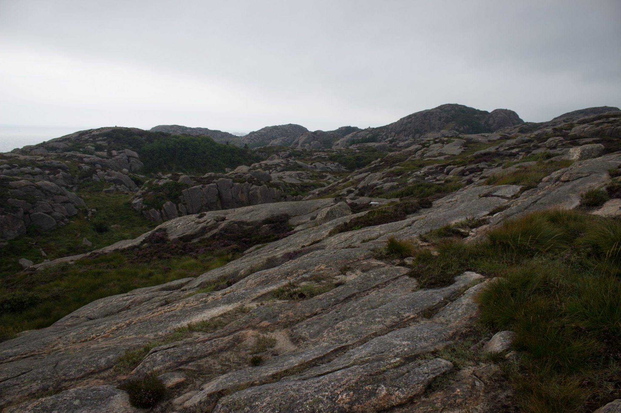 Wanderungen beim Kap Lindesnes, südlichster Punkt Norwegens, am Südkap in Norwegen, Wanderweg führt über große Felsen, grüne Vegetation an der Küste