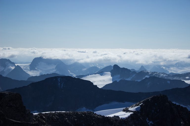 Wanderung auf den höchsten Berg Norwegens - der Galdhøpiggen ab Spiterstulen im Jotunheimen Nationalpark, auch höchster Berg Skandinaviens und Nordeuropas mit 2469 Höhenmetern, Wanderer genießen beeindruckende Aussicht auf die Bergwelt am Gipfel des Galdhøpiggen bei schönstem Sonnenschein