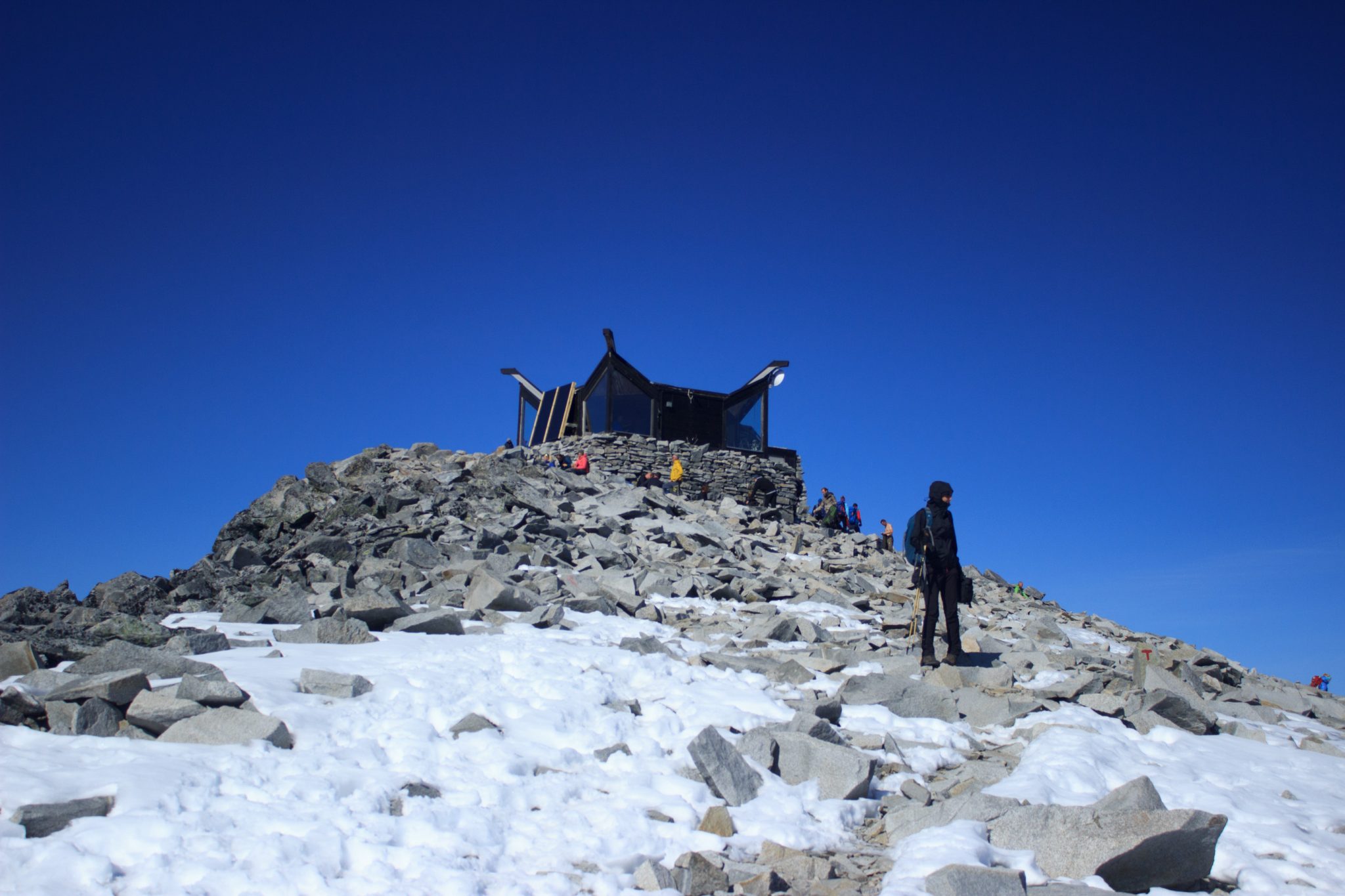 Wanderung auf den höchsten Berg Norwegens - der Galdhøpiggen ab Spiterstulen im Jotunheimen Nationalpark, auch höchster Berg Skandinaviens und Nordeuropas mit 2469 Höhenmetern, Wanderer genießen beeindruckende Aussicht auf die Bergwelt am Gipfel des Galdhøpiggen bei schönstem Sonnenschein